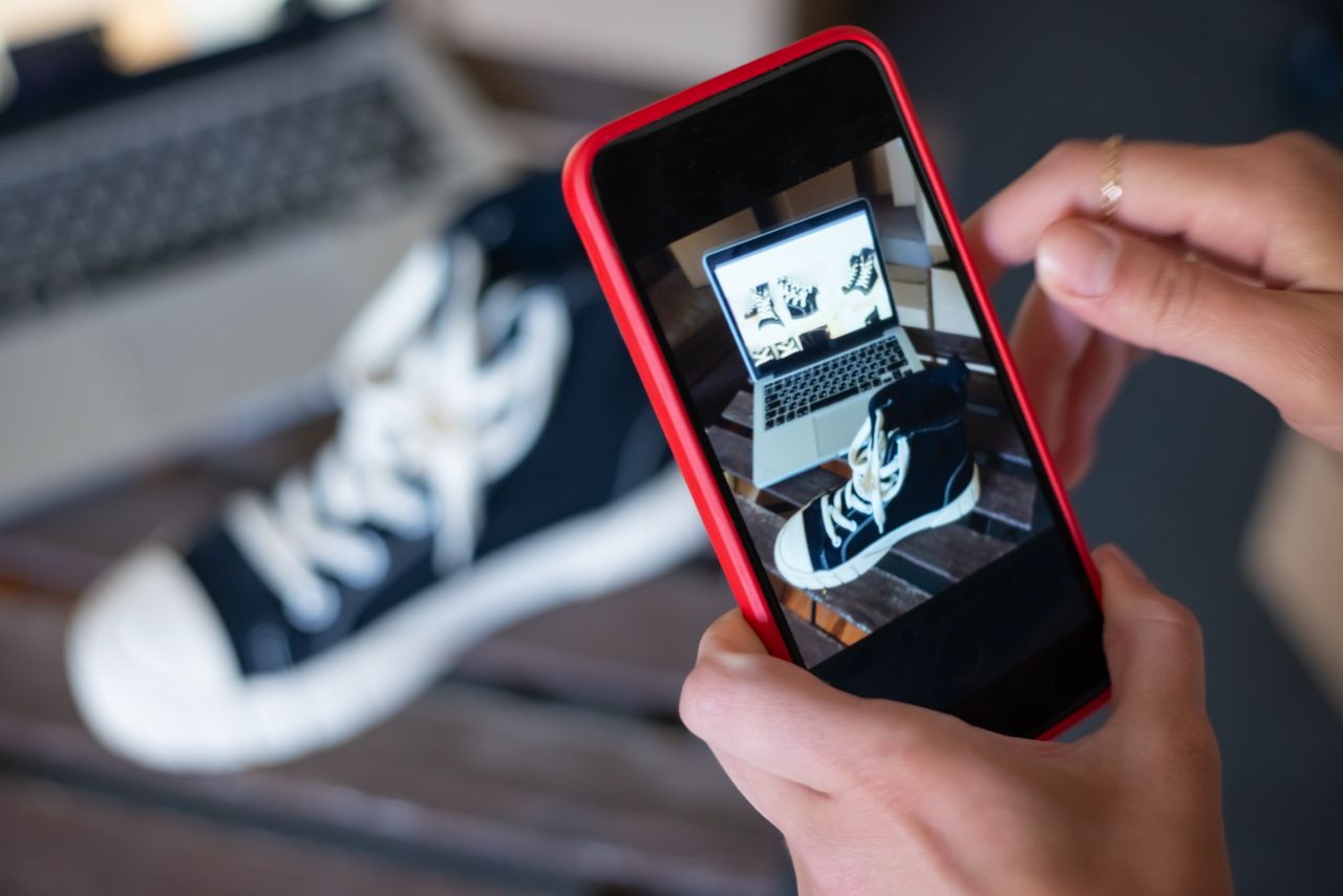 Photographier des sneakers avec un téléphone mobile pour la vitrine d’une boutique en ligne. Le e-commerce dans toute sa splendeur.